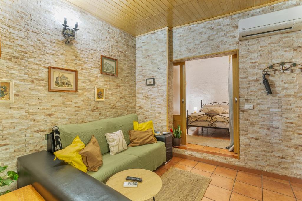 a living room with a green couch and a brick wall at Casa Rosi Cave House in Artenara