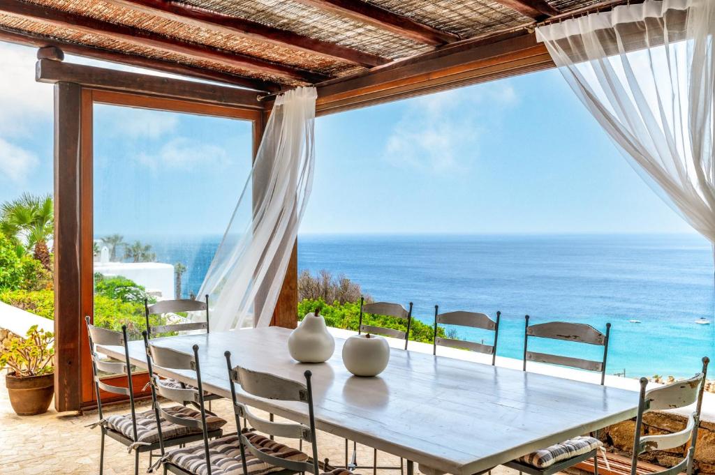 a table with chairs and a view of the ocean at Calma Beach House in Elia Beach