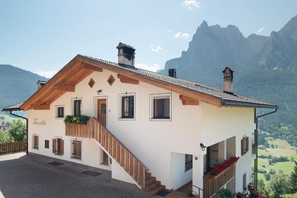 a white house with a staircase and mountains in the background at Thusnelda Apartment D in Siusi