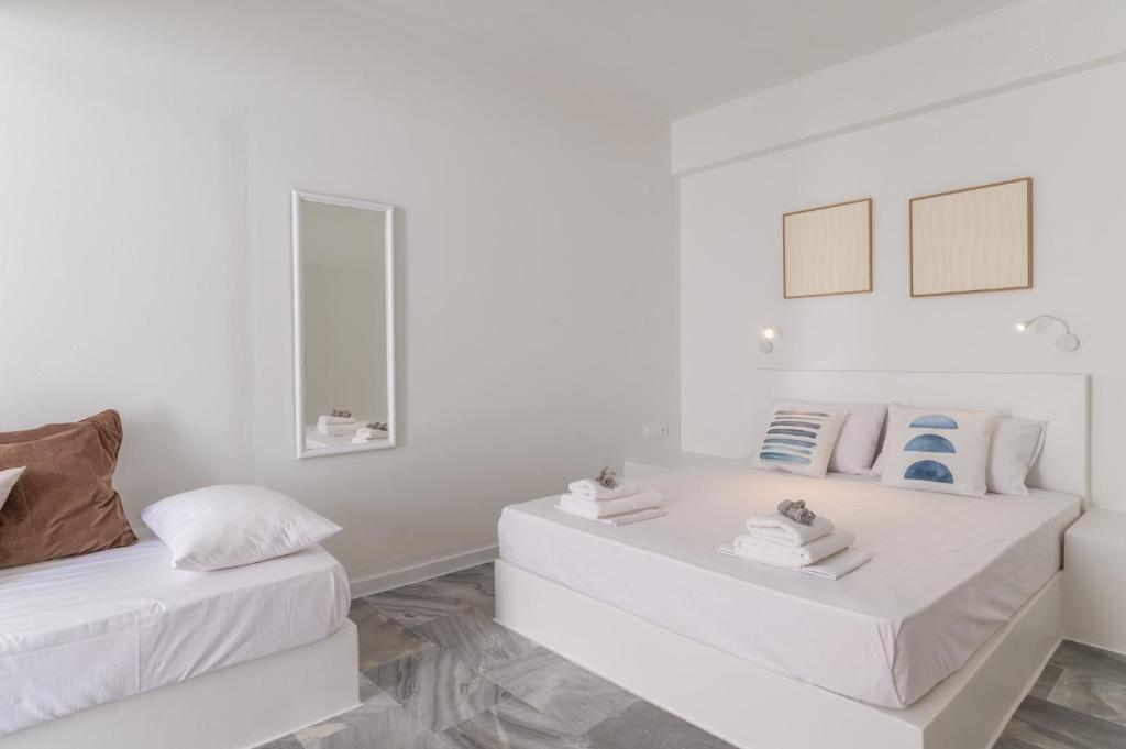 a white room with two beds and a mirror at A Tinian Room 4 in Tinos