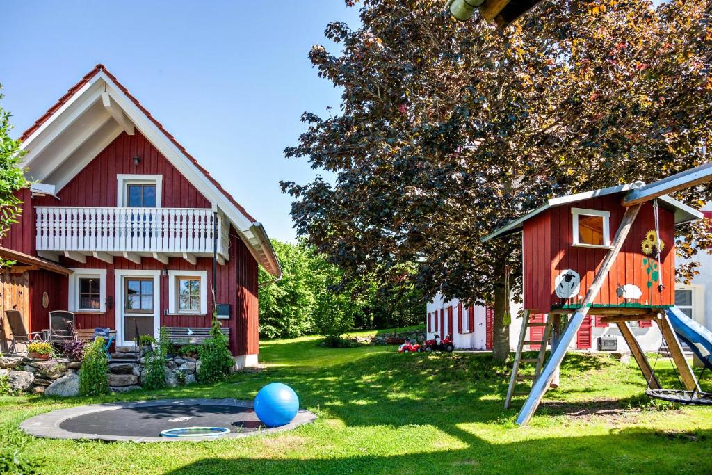 a playground in front of a red house at Naturhäusle Oberschwaben in Ebersbach-Musbach