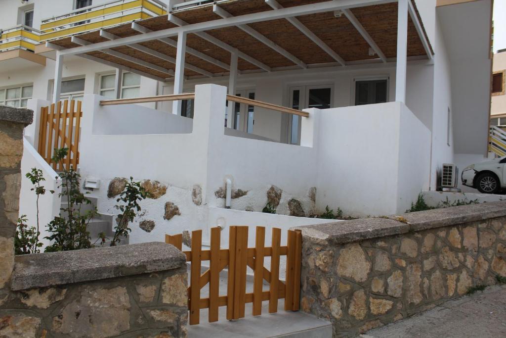a house with white walls and a wooden fence at Kamara Studios in Alinda