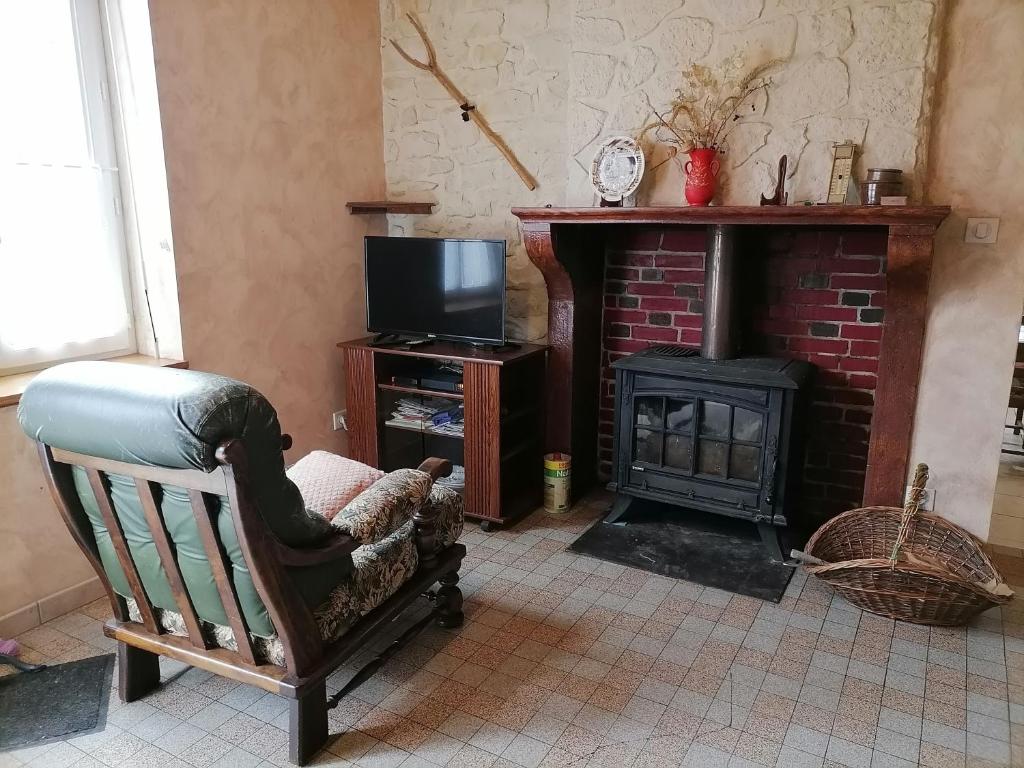 a living room with a chair and a fireplace at Le Gite du Champ de la Croix in Subligny