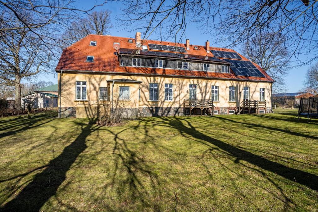 a large house with a red roof on a grass field at Gutshaus Meerzauber in Altenkirchen