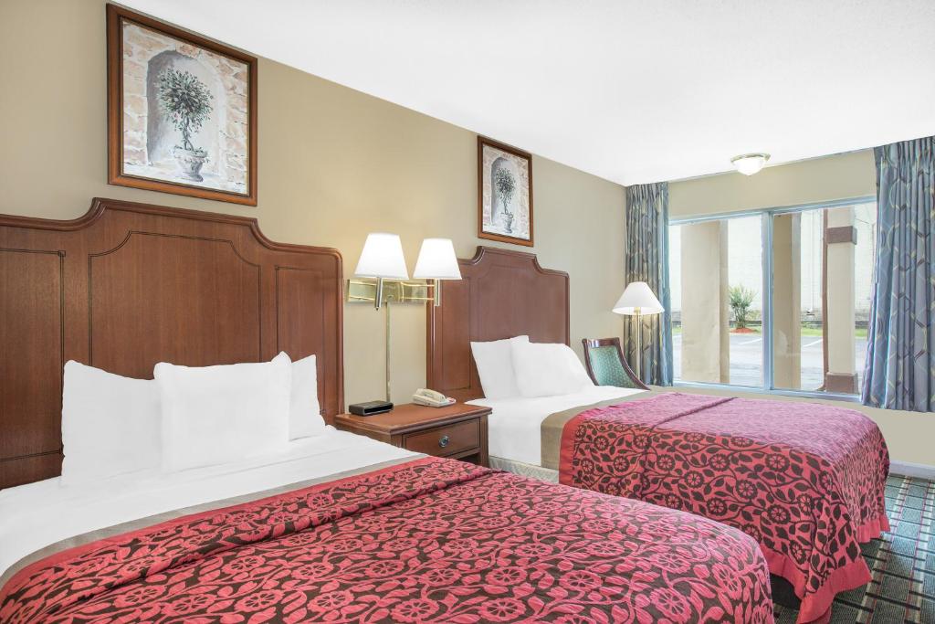 a hotel room with two beds with red sheets at Meridian Inn in Meridian