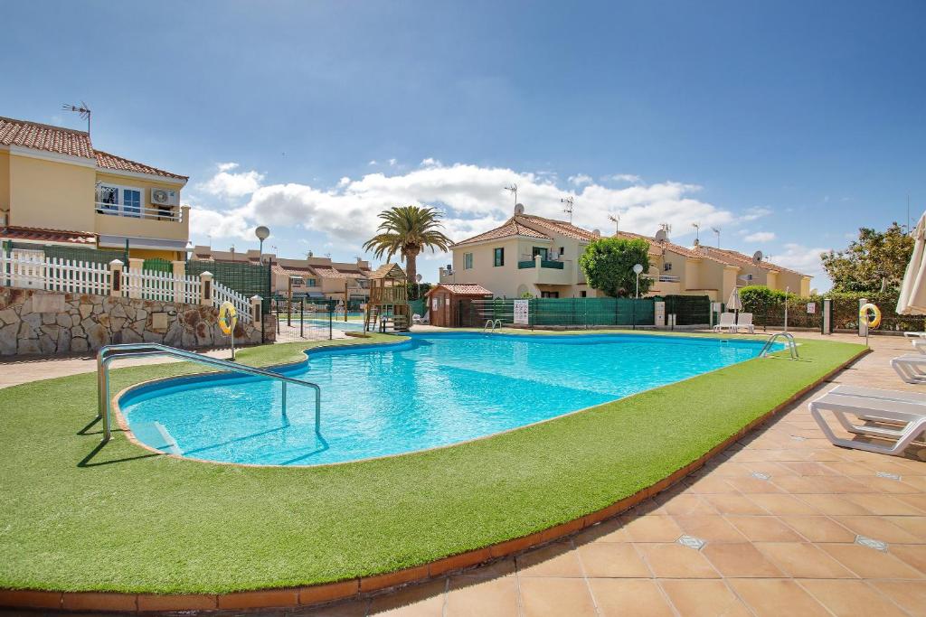 a large swimming pool with green grass and houses at Exclusive Sonemar in Maspalomas