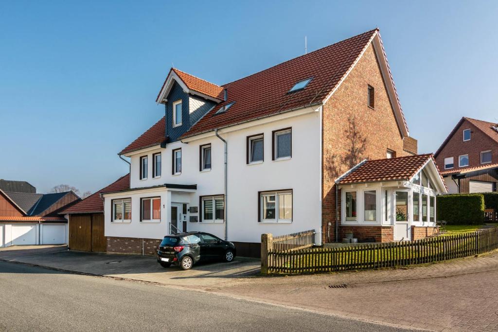a white house with a car parked in front of it at Apartment auf dem Land in Einbeck