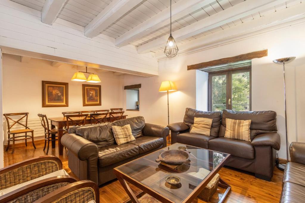 a living room with leather furniture and a table at Casa aranesa en centro de Arties in Arties