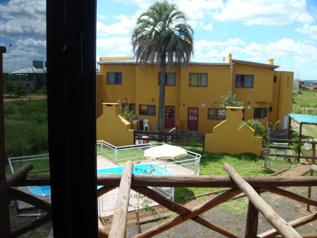 una casa amarilla con una palmera y una piscina en Yataí Casas en Colón