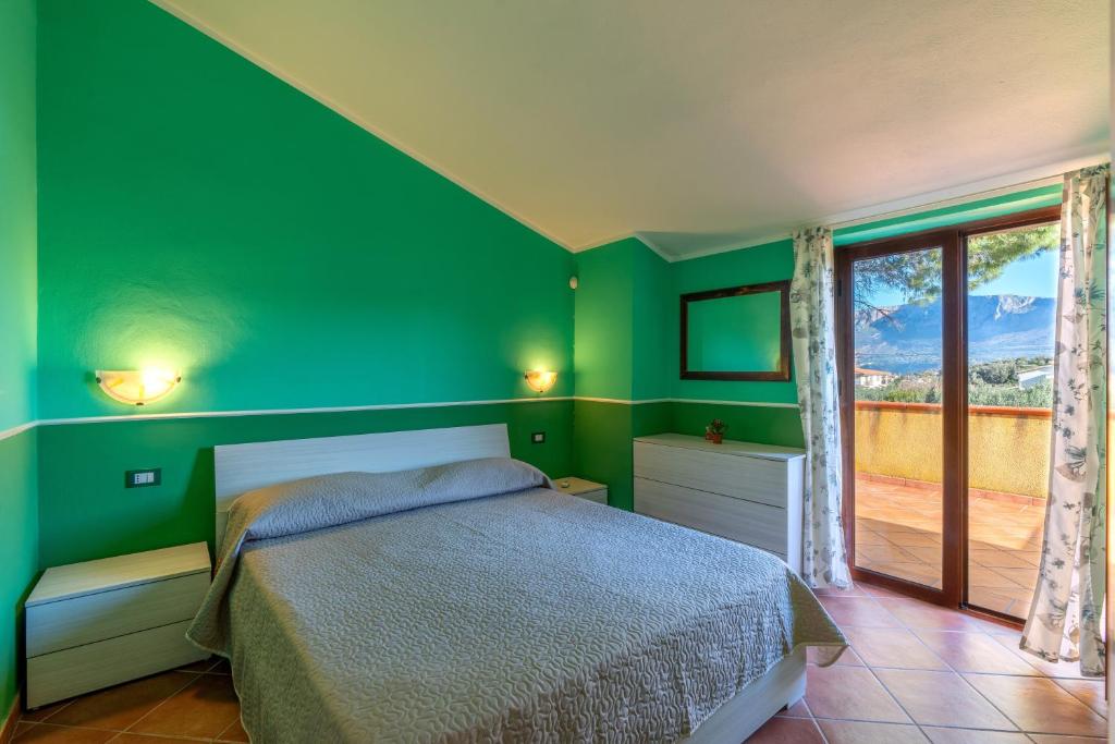 a bedroom with green walls and a bed and a window at Casa Delle Pomelie in Trappeto