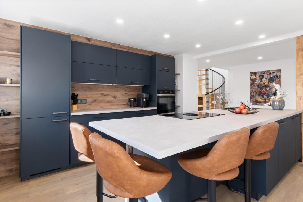 a kitchen with a white counter and some chairs at Fewo Bergfeld in Mosbach