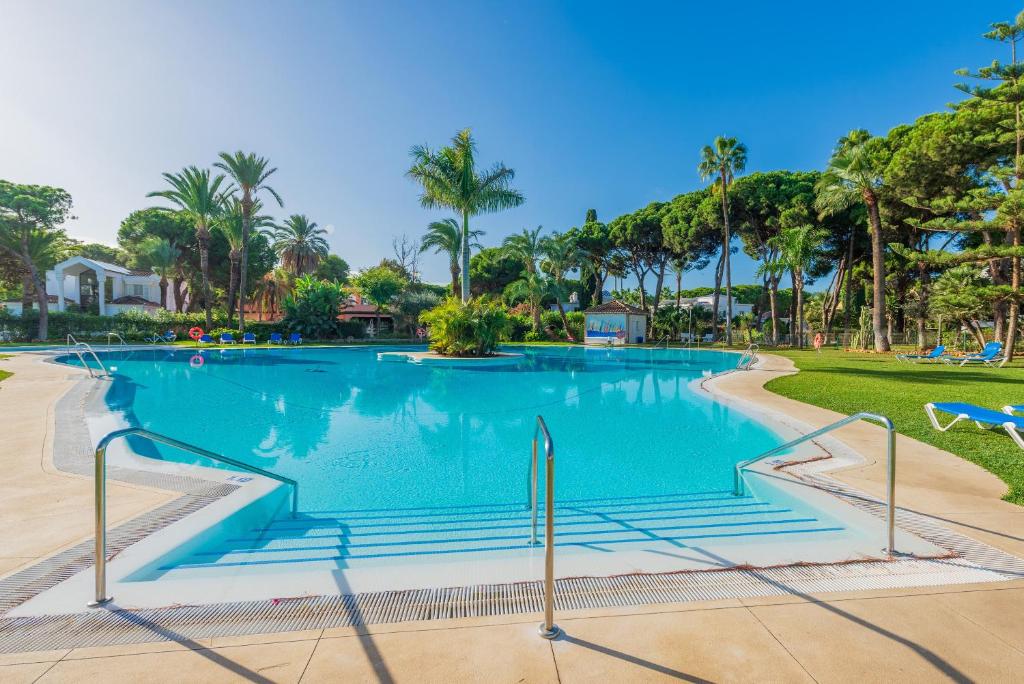 a large swimming pool in a resort with palm trees at Penthouse Jacaranda in Estepona