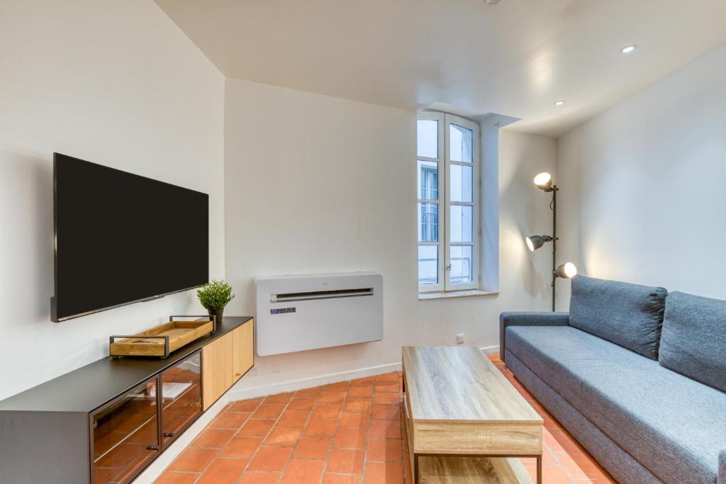 a living room with a blue couch and a tv at La Reine in Béziers