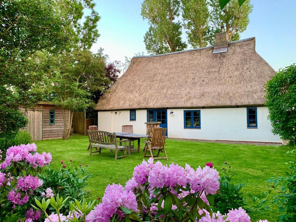 a house with a thatched roof with a table and chairs at Reetdachkate Müllerhaus von 1860 in Thalingburen