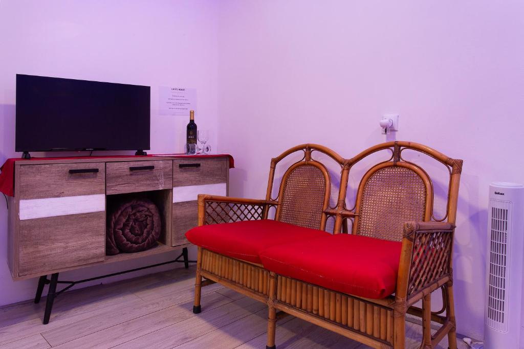 a living room with a tv and a chair with a red cushion at Luci's House B in São Jorge