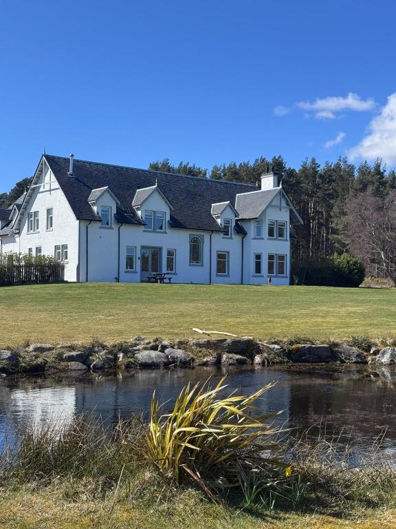 a white house with a pond in front of it at Daviot Lodge in Inverness