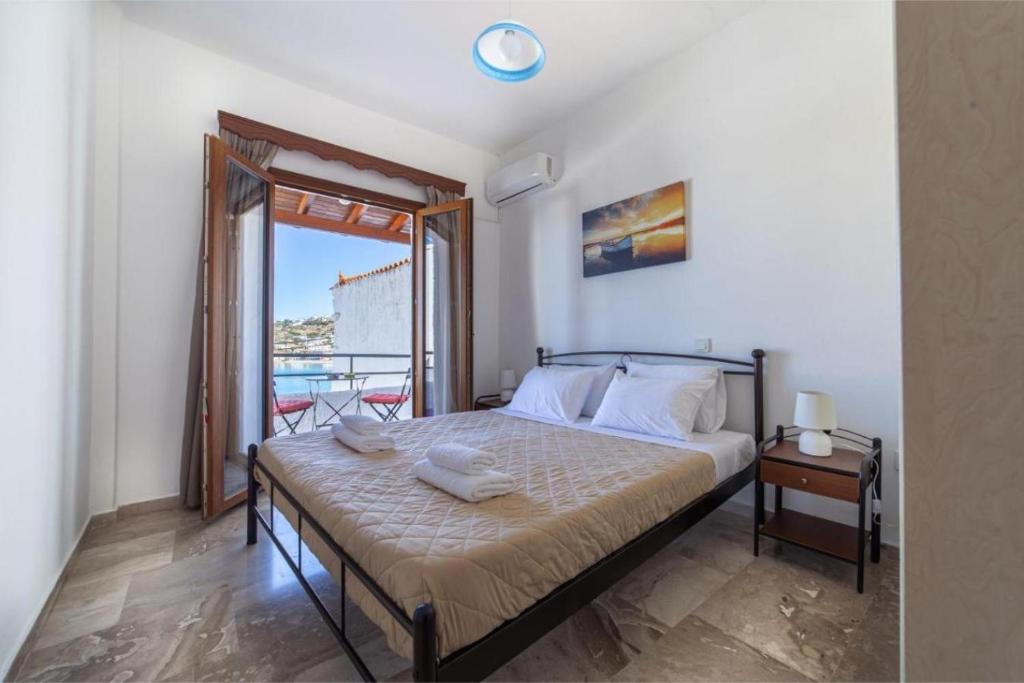 a bedroom with a bed with a view of a balcony at Virginia’s house in Andros