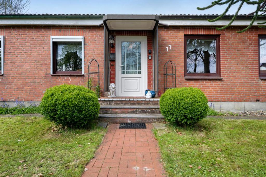 a brick house with a dog sitting in front of the door at Ferienwohnung Alberto in Drelsdorf