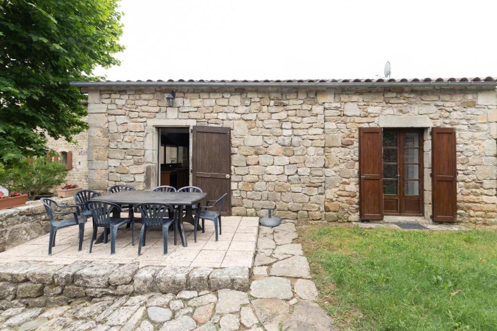 a table and chairs in front of a stone building at Les Sources Gîte La Grange in Chambonas