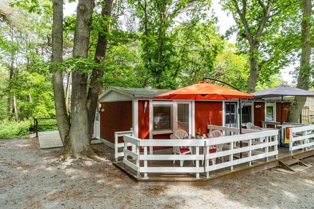 a small cabin with a white fence and an orange umbrella at Bungalow Uschi - Bgl 29 in Dranske