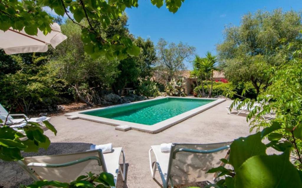 a swimming pool in a yard with two lawn chairs at Es Romagueral in Artá