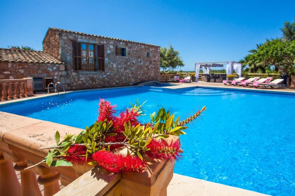 a villa with a swimming pool with red flowers at Casa s’Hort - Can Rita in Llombarts
