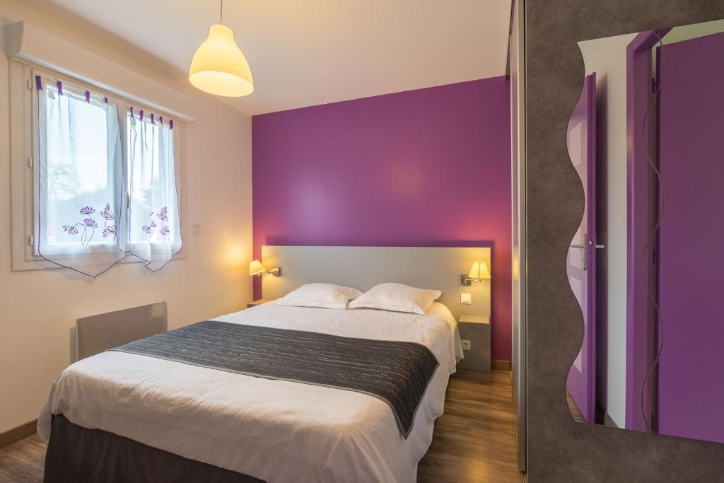 Un dormitorio con una pared morada y una cama. en Fouras, en Saint-Simon-de-Bordes