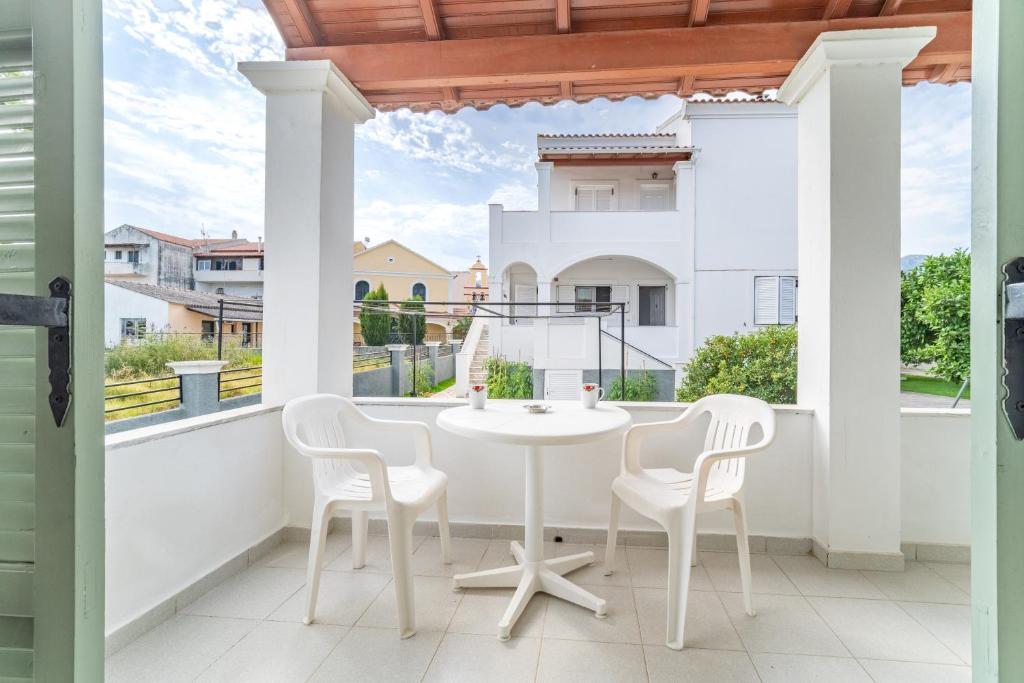 a white table and chairs on a balcony with a view at Olivea Studio 2 in Acharavi