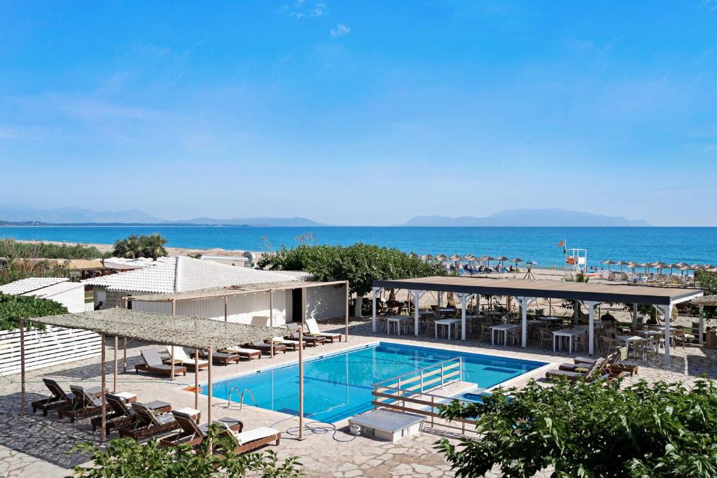 a swimming pool with chairs and the ocean in the background at Iguana studio 5 in Preveza