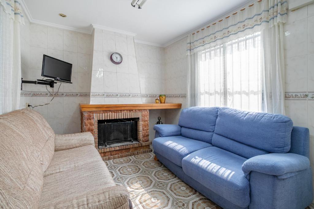 a living room with a blue couch and a fireplace at Geranio in Caserío Bacarot