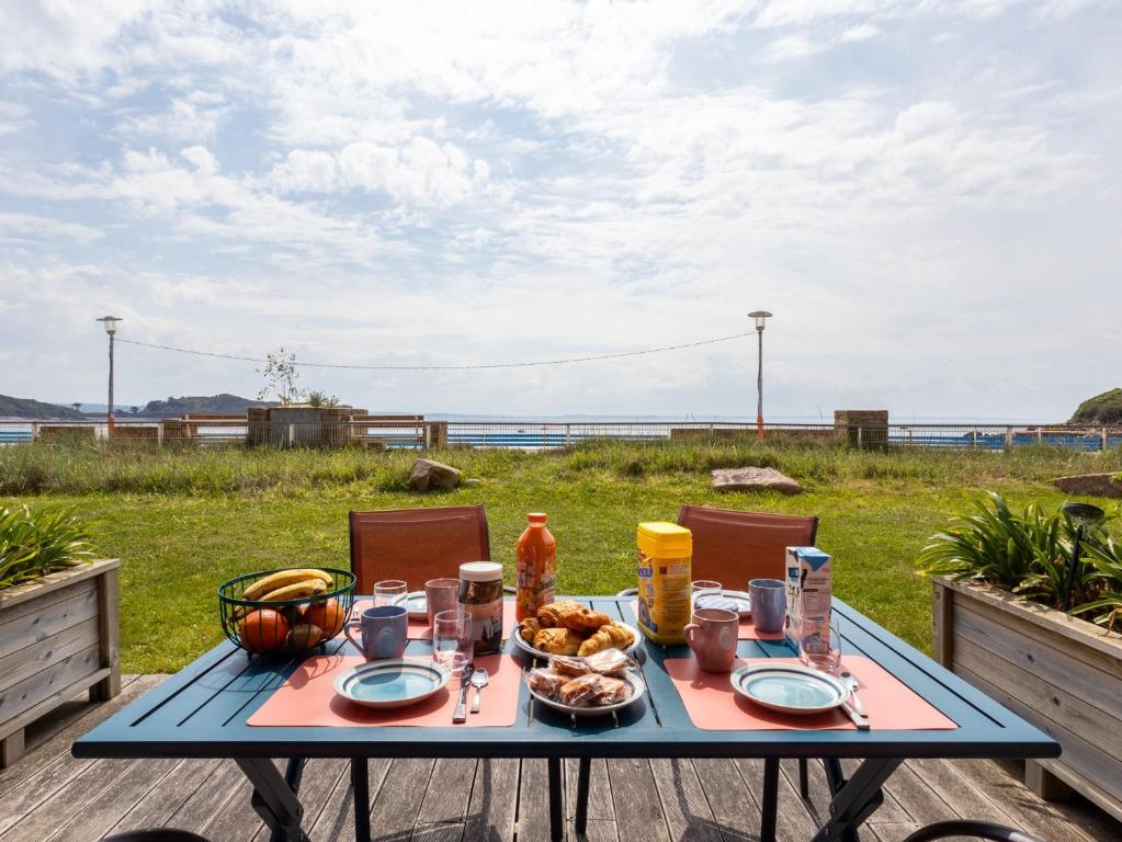 a table with food on it with a view of the ocean at Pieds Dans L'eau Madame est Servie in Trébeurden