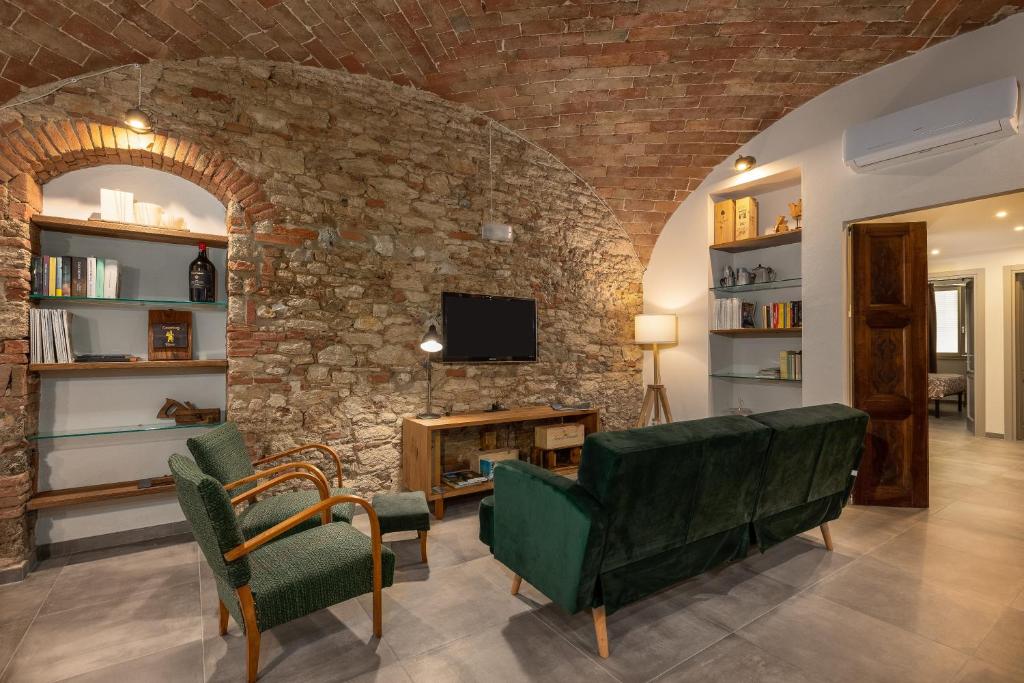 a living room with two green chairs and a stone wall at Casa Masoni in Colle di Val d'Elsa