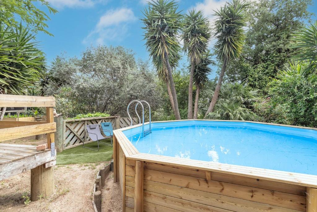 a swimming pool in a backyard with palm trees at Petite maison de bois in Banyuls-dels-Aspres