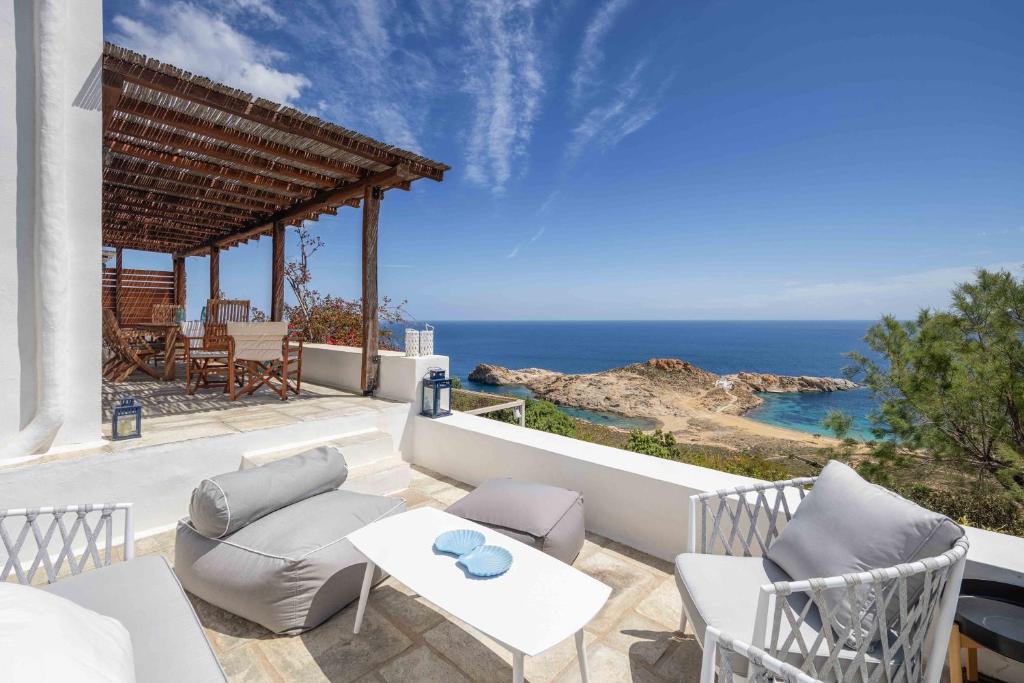 a patio with chairs and a table and the ocean at Villa Agios Sostis in Serifos Chora