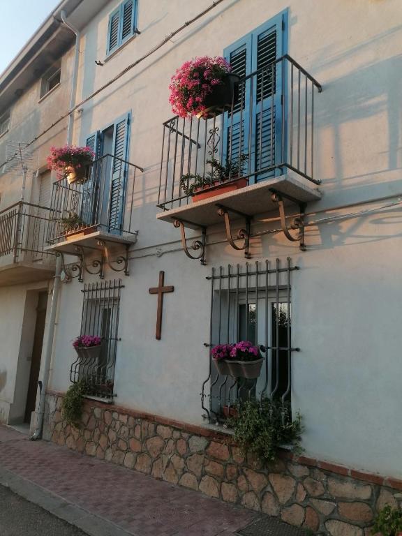 a building with flowers on the balconies and a cross at Casa vacanze Bau Mela in Villanova Strisaili