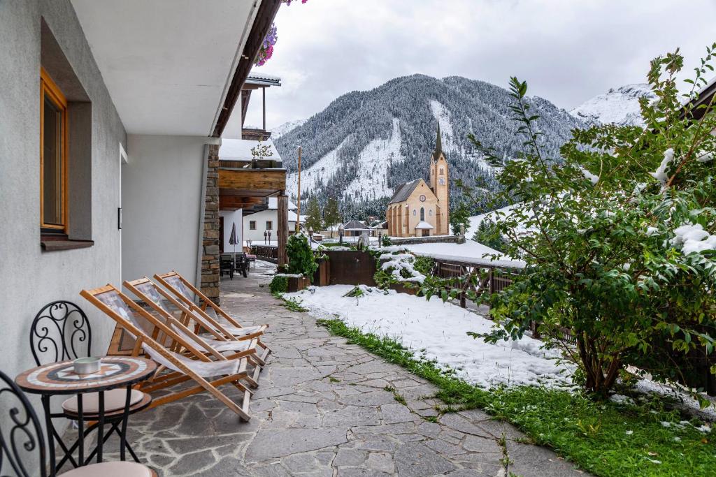 a patio with chairs and a table and a mountain at Hotel Sonnblick - Wohnung Klaus in Kartitsch