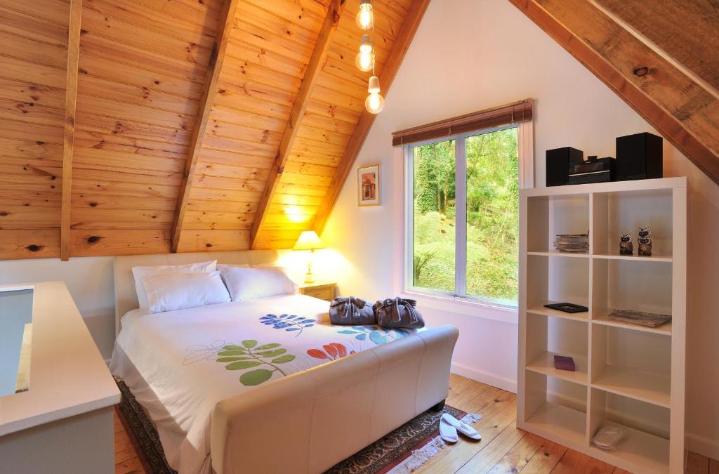 a bedroom with a bed and a window at Santosa Cottage Sassafras in Olinda