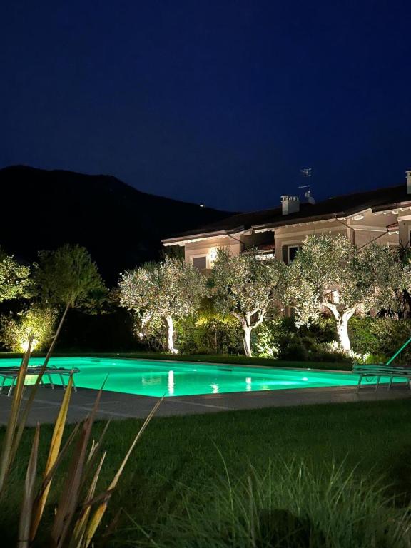 a night view of a pool with trees and a building at La dolce vita - Lake Iseo in Paratico