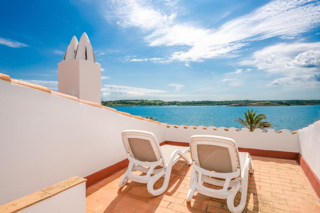 two chairs on a balcony with a view of the water at Casa Ullastre de Fornells in Fornells