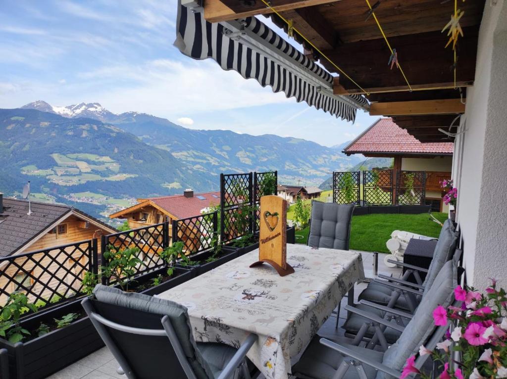 a table and chairs on a balcony with mountains at Ferienwohnung Zillertalblick in Stummerberg