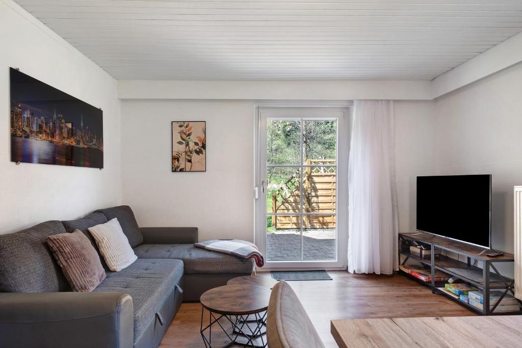 a living room with a couch and a tv at Ferienwohnung am Waldrand in Alpirsbach