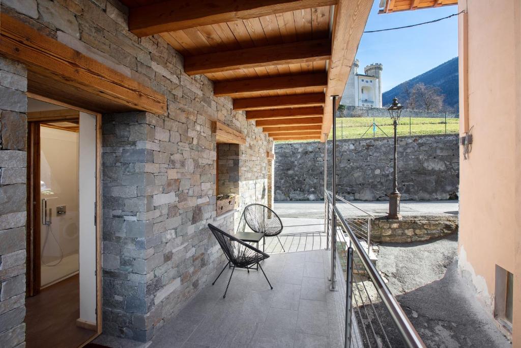 a patio with a chair and a stone wall at Alpine A-S in Aymavilles
