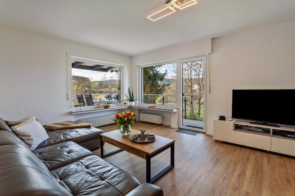 ein Wohnzimmer mit Ledersofa und Fernseher in der Unterkunft Sauerlandrefugium in Medebach