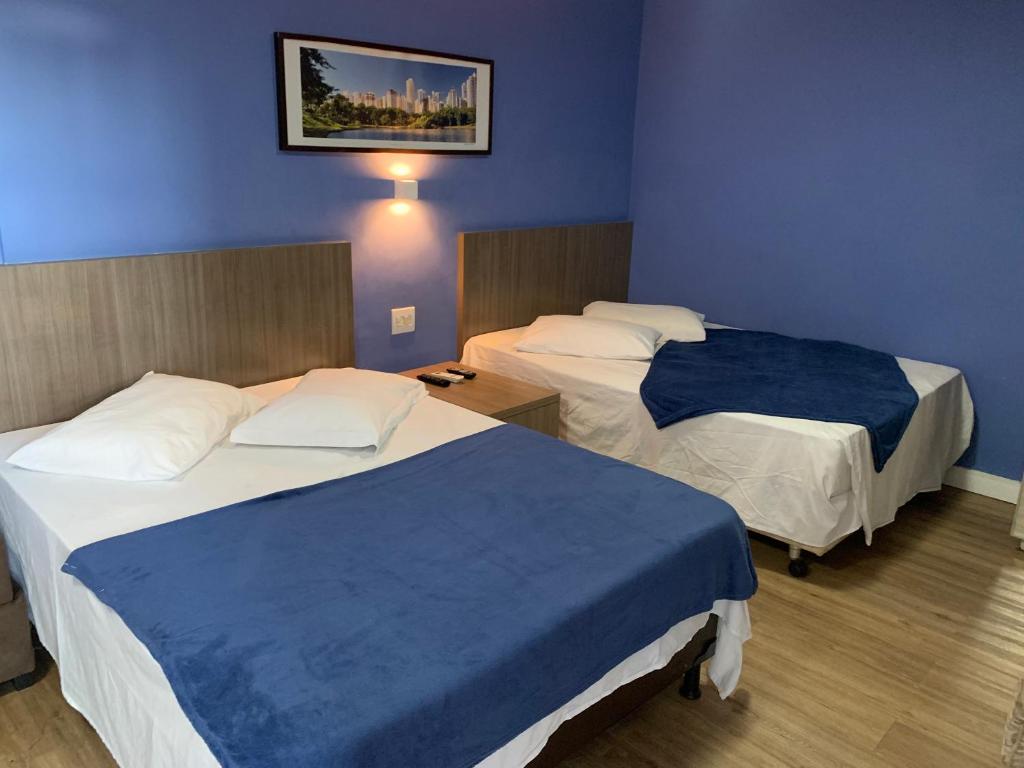 two beds in a hotel room with blue walls at 701 - Flat Temporada em Goiania-proximo ao Parque Areião in Goiânia
