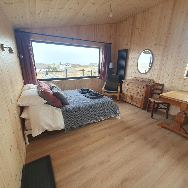 a bedroom with a bed and a large window at The Other Wee Red Cabin in Dunvegan