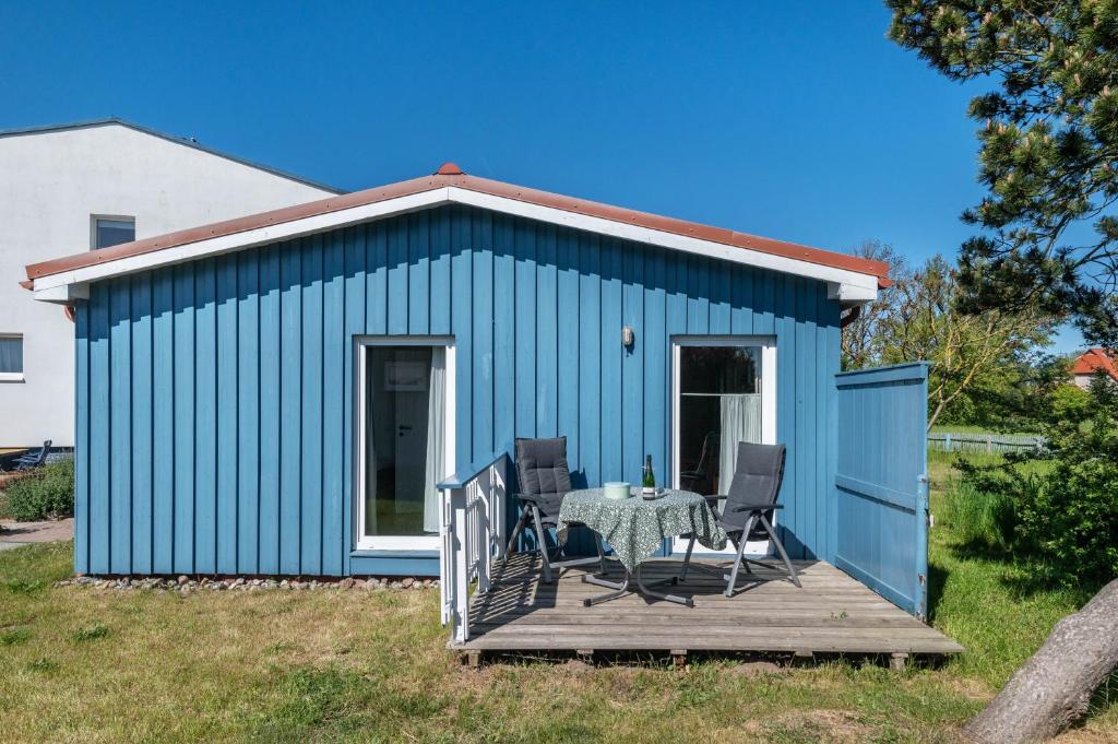 a blue shed with a table and chairs on a deck at Möve Aba Bungalow 61 in Rerik