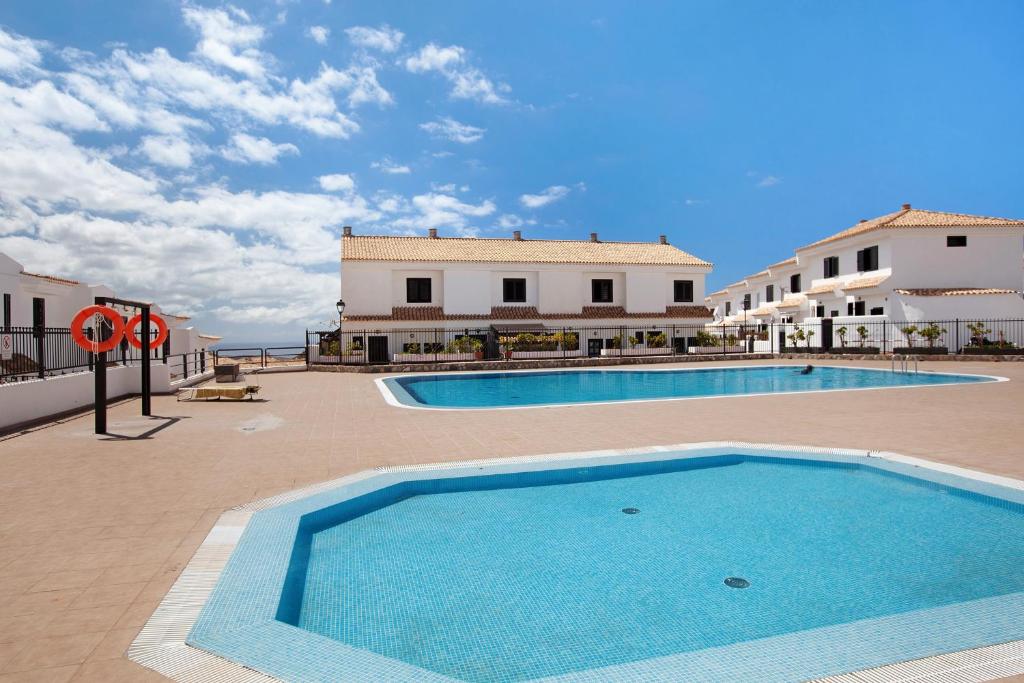 a large swimming pool in a courtyard with buildings at Casa Dos Ángeles in Arona