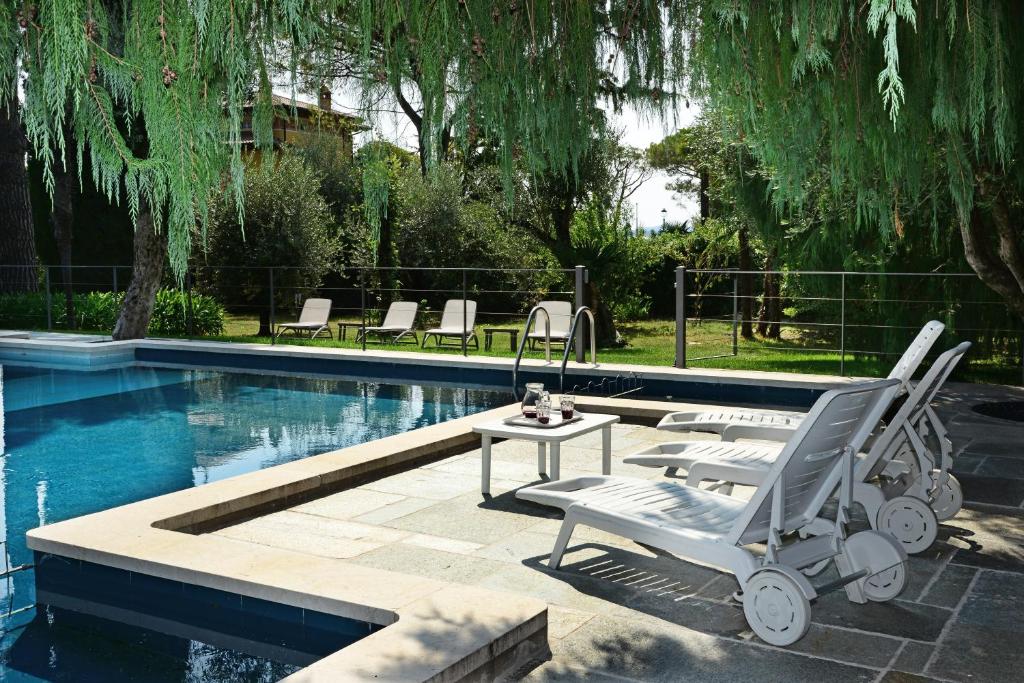 a pool with two chairs and a table next to it at Al Segnavento Roccafredda in Toscolano Maderno