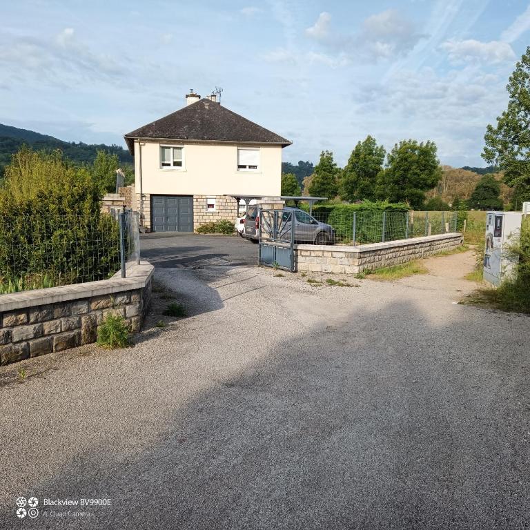 a house with a car parked in front of a driveway at La Clematite d'Olt in Saint-Côme-dʼOlt
