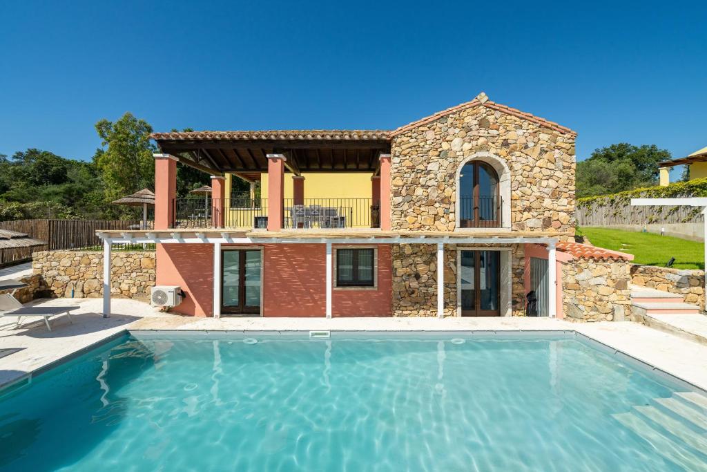 a villa with a swimming pool in front of a house at Pretziosa in Castiadas